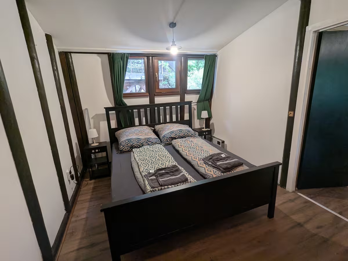 Hauptschlafzimmer mit Doppelbett und grünen Vorhängen